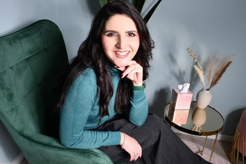 Morena Tigano Bild von Morena Tigano, die in ihrem Büro sitzt und lächelnd in die Kamera schaut.